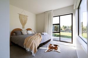 a bedroom with a bed and a large window at Modern Raglan Hideaway in Raglan