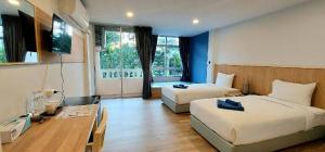 a hotel room with two beds and a television at Karon Living Room - SHA Plus in Karon Beach