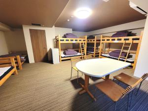 Zimmer mit Etagenbetten sowie einem Tisch und Stühlen in der Unterkunft K's House Nikko - Kinugawa Onsen Hostel in Nikko