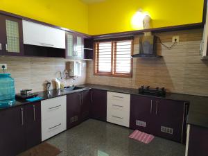 a kitchen with brown cabinets and a yellow wall at Nandana Home stay in Mysore