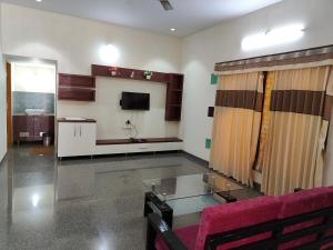 a living room with a red couch and a tv at Nandana Home stay in Mysore