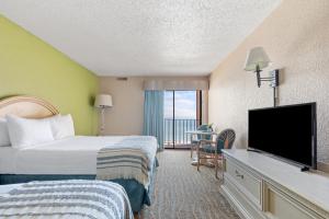 a hotel room with two beds and a flat screen tv at Sandcastle Oceanfront Resort at the Pavilion in Myrtle Beach