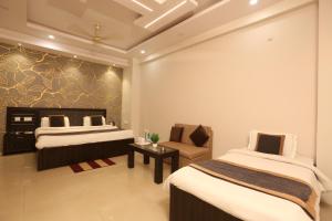 ein Hotelzimmer mit 2 Betten und einem Stuhl in der Unterkunft Hotel Nexus in Lucknow