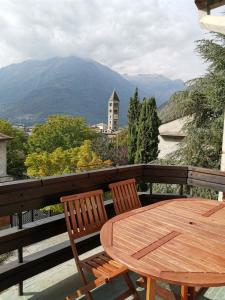een houten tafel en stoelen op een balkon met een berg bij La Casa Del Quirino in Tirano
