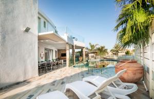 a patio with white chairs and a swimming pool at Yalarent Enorma complex with shared heated pool in Eilat