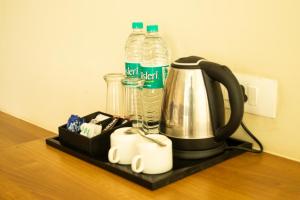 a counter with a coffee maker and bottles of water at Chang's Garden & Resort in Golāghāt