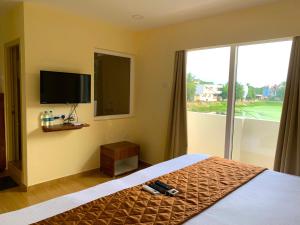 a bedroom with a bed and a tv and a window at Hotel Ramakrishna in Mahabalipuram