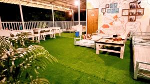 un patio con césped, mesas y sillas en ROOTSVILLA VAGATOR - Longstays, Coworking Backpacker's Hostel en Vagator