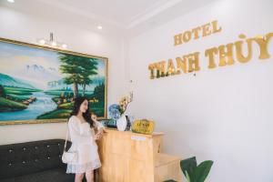 a woman standing at a podium in a room with a painting at Khách sạn Thanh Thùy Đà Lạt in Xuan An