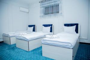 2 łóżka pojedyncze w pokoju z niebieskim dywanem w obiekcie Lola Kokand Hotel w mieście Kokand
