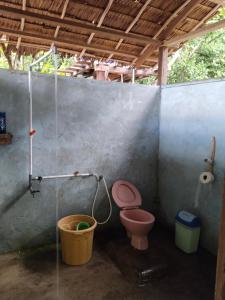 a bathroom with a pink toilet and a bucket at Gibran guest house in Kri