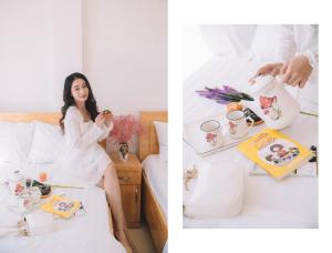 a woman in a white dress sitting on a bed eating food at Khách sạn Thanh Thùy Đà Lạt in Xuan An