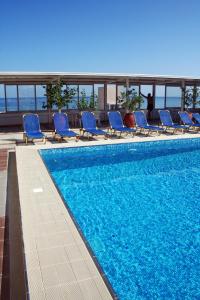 a swimming pool with blue lounge chairs on a building at Achillion Palace in Rethymno