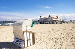 a chair on the beach with a pier in the background at Ledwig, Villa Medici in Ahlbeck