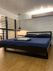 1 dormitorio con 1 cama grande con sábanas azules en JORA LOFT- modern industrial apartment 1-A, en Dagupán