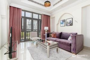 a living room with a purple couch and a tv at Dream Inn Apartment- Tajer Souk Al Bahar in Dubai