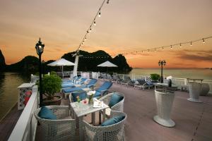 una terraza con sillas y mesas y vistas al agua en Hermes Cruises, en Ha Long