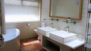 a bathroom with two sinks and a tub and a mirror at Atlantic Villa Boutique Guesthouse in Swakopmund