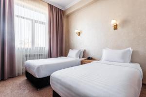 une chambre d'hôtel avec deux lits et une fenêtre dans l'établissement Western Suites Hotel, à Tachkent