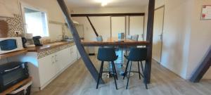 a kitchen with a table and stools in a room at Appartement Ecuries du Val de Mai, 10pers in Talmas