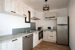 a kitchen with a stainless steel refrigerator and wooden cabinets at Via Mare in Sainte-Lucie de Porto-Vecchio