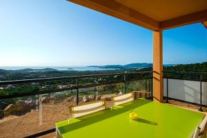 una mesa verde en un balcón con vistas al océano en Via Mare en Sainte-Lucie de Porto-Vecchio