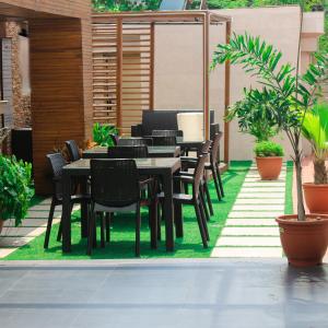 um pátio com mesas pretas, cadeiras e plantas em Victoria Crown Plaza Hotel em Lagos