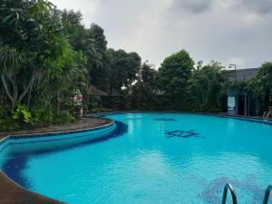 uma grande piscina azul com árvores ao fundo em The Green Winotosastro Hotel Yogyakarta em Yogyakarta