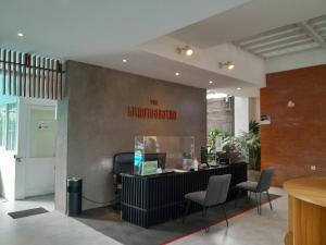 The Green Winotosastro Hotel Yogyakarta في يوغياكارتا: غرفة انتظار مع كونتر وكراسي في مبنى