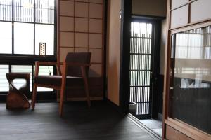 a room with a chair and a table and windows at Brian Private Machiya in Higashiyama in Kyoto