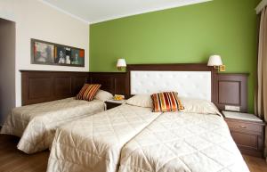 two beds in a room with green walls at Achillion Palace Hotel Rethymno City Center in Rethymno