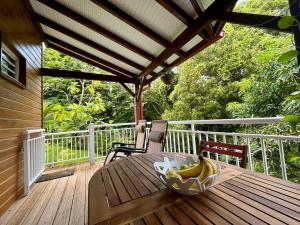 a table with a bowl of bananas on a deck at Mahogany Lodge - Oasis cosy in Rivière-Pilote