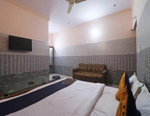 索尼帕特的住宿－Hotel Shri Ram Residency, Sonipat, Haryana，一间卧室配有一张床、一张沙发和一台电视