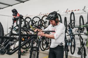 Um homem de capacete está a trabalhar numa bicicleta. em Peaks Place Apartments & SPA em Laax