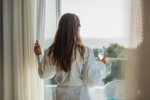 Una donna che tiene un bicchiere di vino e guarda fuori dalla finestra. di Iberostar Selection Llaut Palma- Adults Only a Playa de Palma