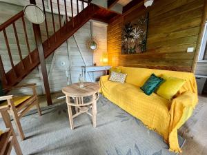 ein Wohnzimmer mit einem gelben Sofa und einem Tisch in der Unterkunft Mahogany Lodge - Oasis cosy in Rivière-Pilote