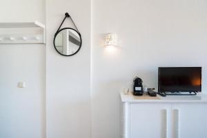 a room with a tv and a mirror on a wall at SILCHORO - Estúdio remodelado com AC e piscina em Albufeira in Albufeira