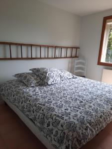 a bed with a black and white comforter and a window at La Muchette, maison au calme 3 chambres 2 salles d'eau in Juvigny