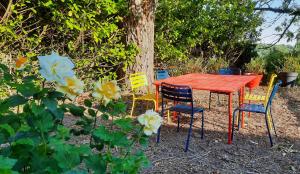 a red table and chairs sitting around a tree at La Muchette, maison au calme 3 chambres 2 salles d'eau in Juvigny