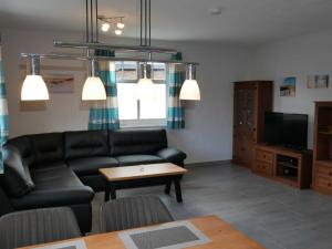 sala de estar con sofá negro y mesa en Ferienhaus Sellin, en Ostseebad Karlshagen