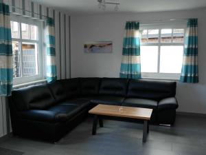 a black leather couch in a living room with windows at Ferienhaus Sellin in Ostseebad Karlshagen +14 photos