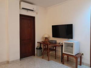 a room with a desk with a television on the wall at The Green Winotosastro Hotel Yogyakarta in Yogyakarta