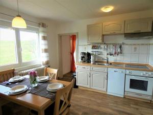 eine Küche mit einem Holztisch und eine Küche mit weißen Geräten in der Unterkunft Ferienwohnung Siglinde Schneider in Freiamt