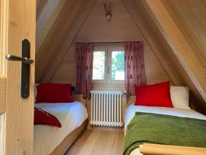 - 2 lits dans une petite chambre mansardée avec fenêtre dans l'établissement Cozy Mountain Chalet, à Cavalese