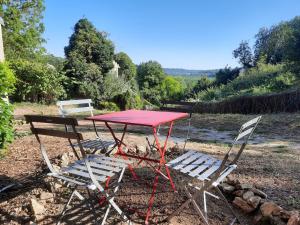 a red picnic table and two chairs in a yard at La Muchette, maison au calme 3 chambres 2 salles d'eau in Juvigny