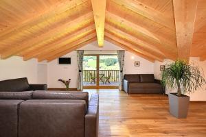 a living room with wooden ceilings and leather couches at Planatschhof in Villnoss