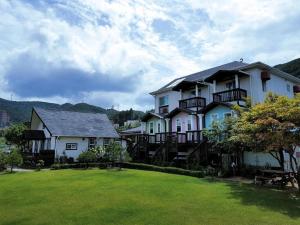 a large white house with a green yard at Daegwallyeong Beautiful Pension in Pyeongchang