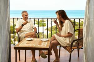 a man and woman sitting on a balcony drinking coffee at Iberostar Selection Andalucia Playa in Chiclana de la Frontera