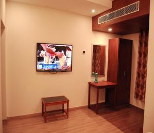 a living room with a tv on the wall at Shivalaya hotel in Pudukkottai