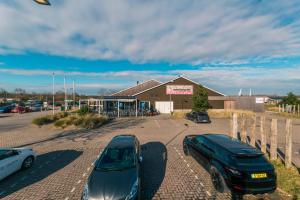 un parking avec deux voitures garées devant un bâtiment dans l'établissement EuroParcs Poort van Zeeland, à Hellevoetsluis